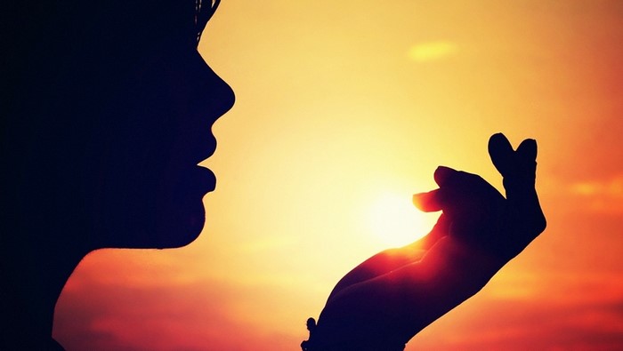 Silhouette of a woman blowing a kiss at sunset