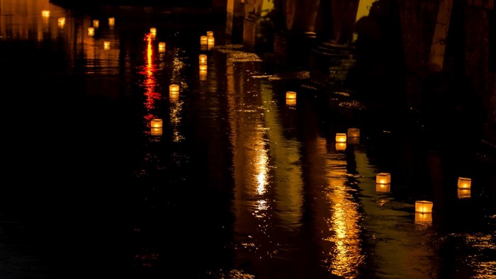Lanterns floating on water at night with reflections