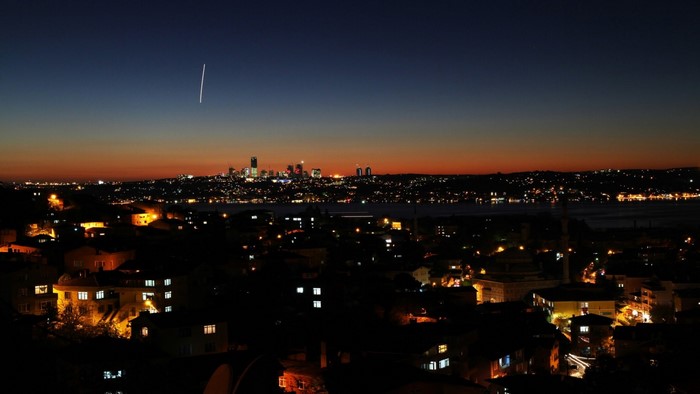 City skyline at dusk with airplane contrail