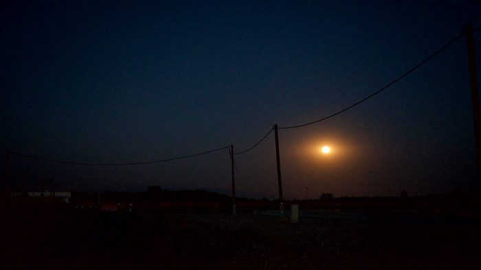 Moonlight over a dark landscape with power lines