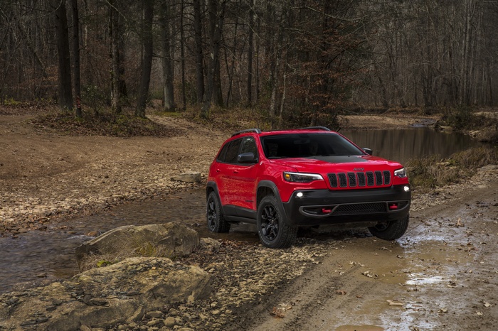 Red Jeep Cherokee on a dirt road near a stream