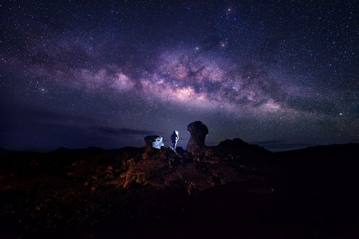 Person standing under the Milky Way galaxy
