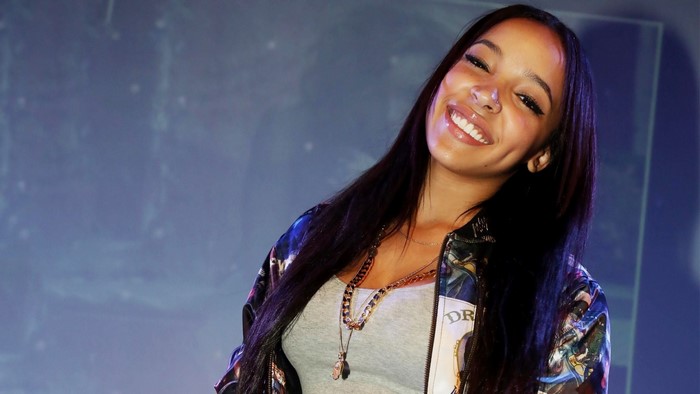 Tinashe Kachingwe smiling, wearing a grey tank top and jacket