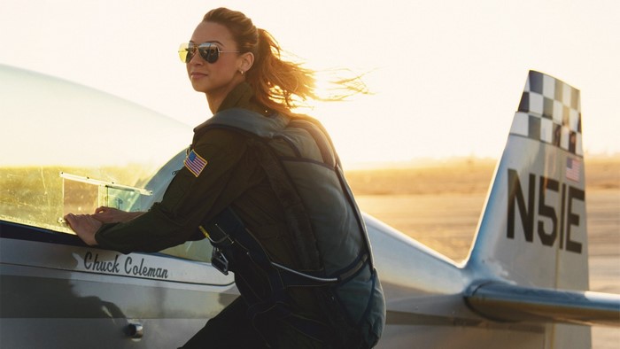 Woman in flight suit leaning on a Chuck Coleman airplane