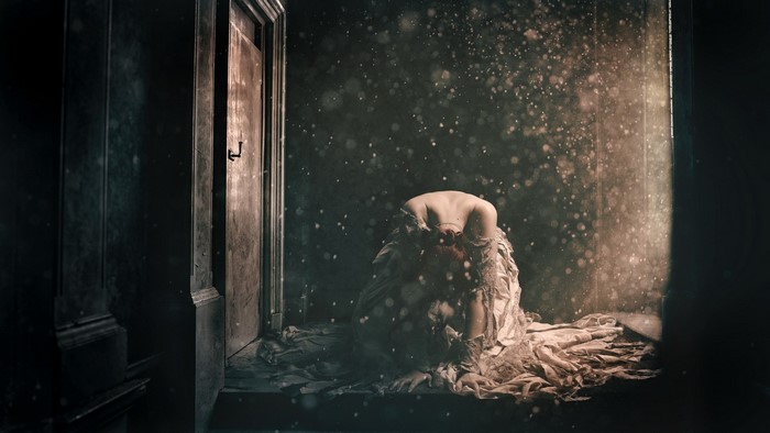 Woman in a tattered dress in a dark room