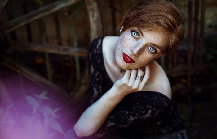 Woman with red hair and freckles wearing a black lace dress