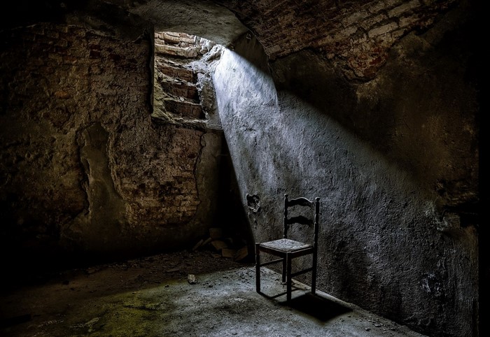 Chair in a dark, ancient cellar with sunlight beam