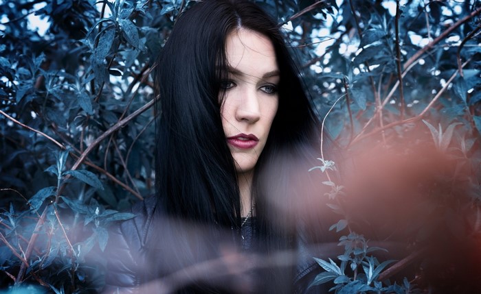 Woman with dark hair in blue foliage
