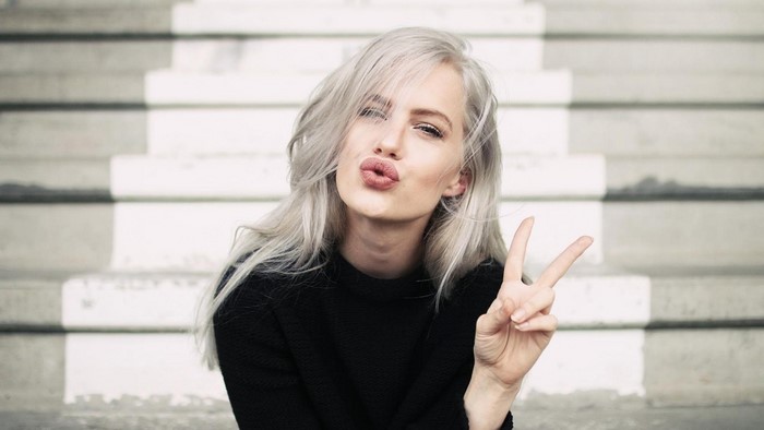 Woman with white hair pouting and making peace sign