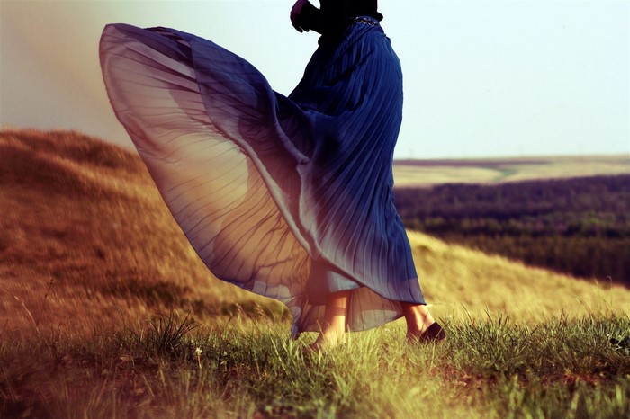 Woman in flowing blue skirt on grassy hill