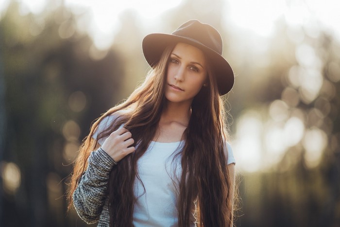 Woman wearing a hat and white shirt with long brown hair