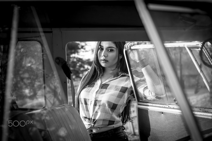 Woman in plaid shirt leaning on car door