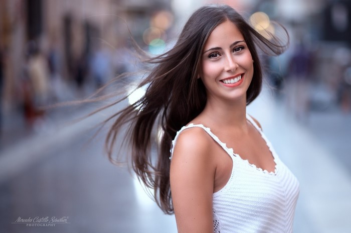 Woman with long brown hair smiling outdoors