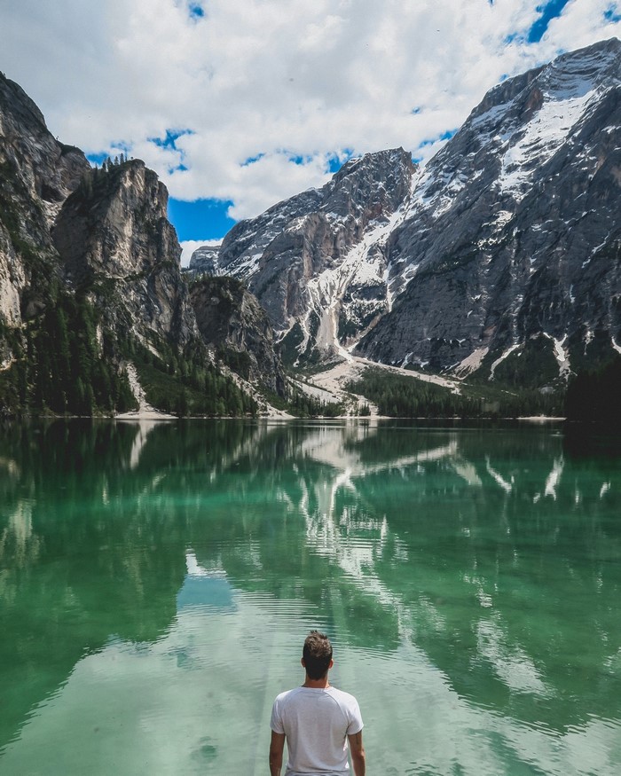 Man looking at a mountain lake reflection