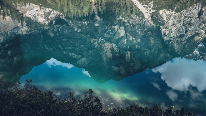 Mountain reflection in a turquoise lake with trees