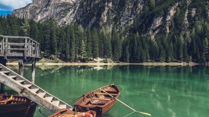 Wooden boats on a clear lake with mountains and trees