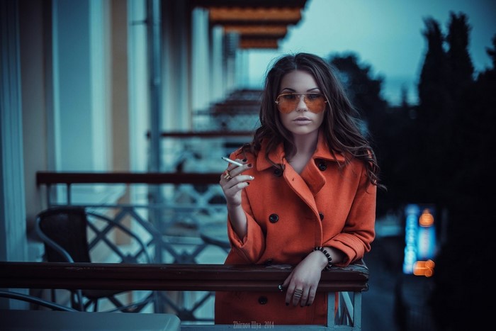 Woman with sunglasses smoking on a balcony