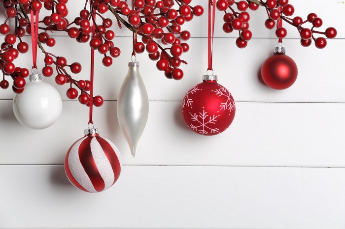 Christmas ornaments and red berries on white wood