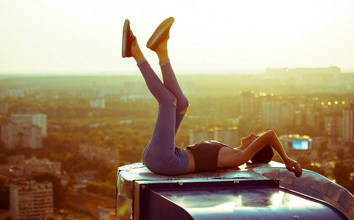 Woman lying on a rooftop with legs in the air