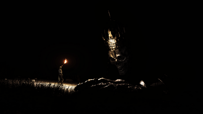 Figure with Torch and Giant Skull in Darkness