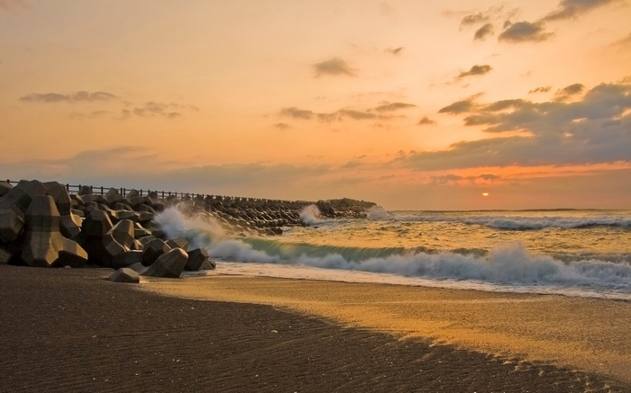 Sunset over a beach with tetrapods and waves