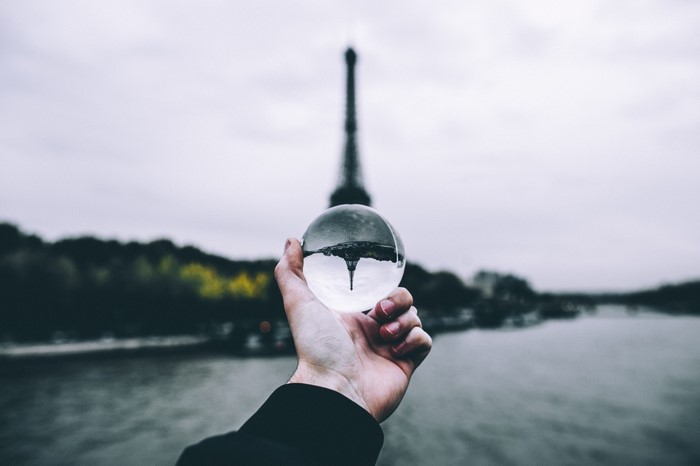 Eiffel Tower reflected in a crystal ball held by a hand
