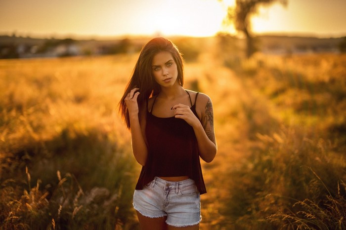 Woman with tattoo in jean shorts at sunset