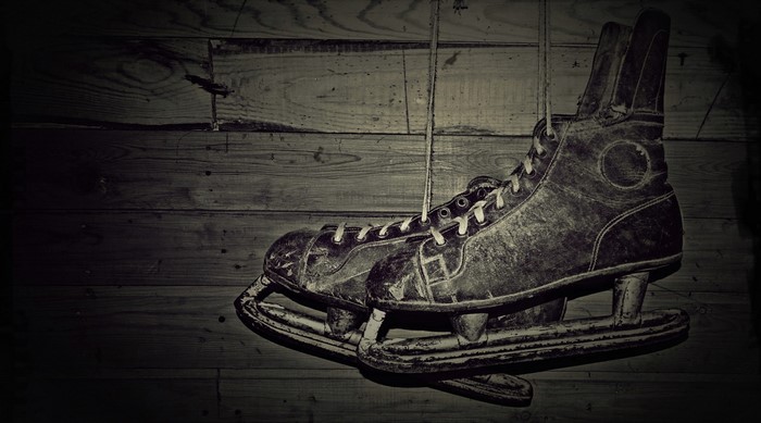 Old ice skates hanging on a wooden wall