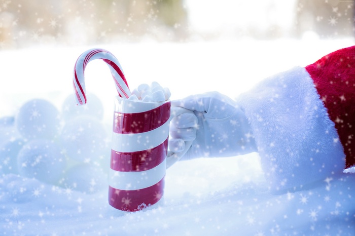 Santa holding a candy cane hot chocolate in the snow