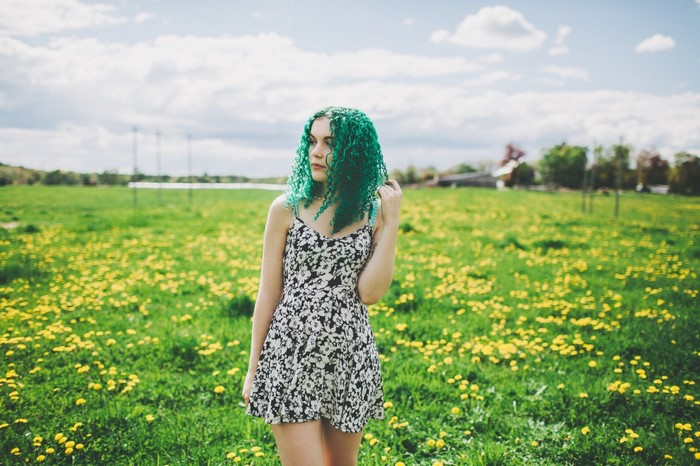 Woman with green dyed hair in a field of flowers