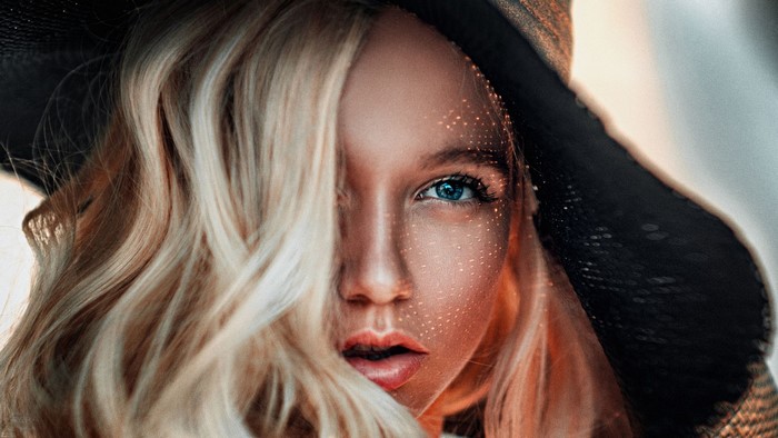 Woman with blonde hair and blue eyes wearing a hat