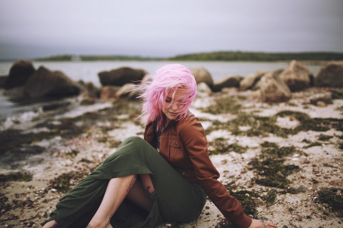 Woman with pink hair sitting on a beach