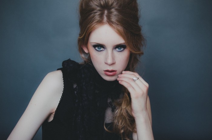 Woman with red hair and blue eyes wearing black dress