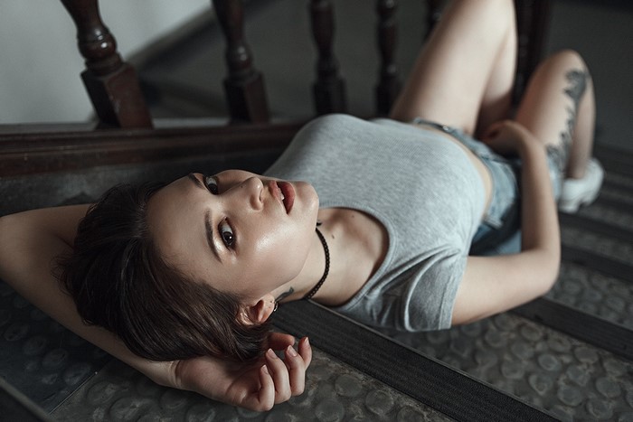 Woman lying on stairs with tattoos