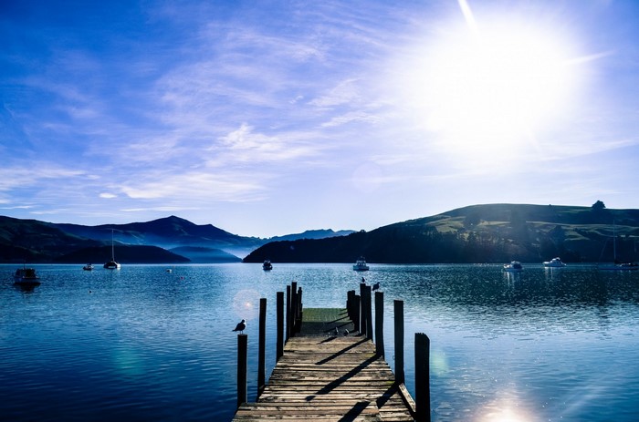 Wooden dock on a calm bay with mountains and boats