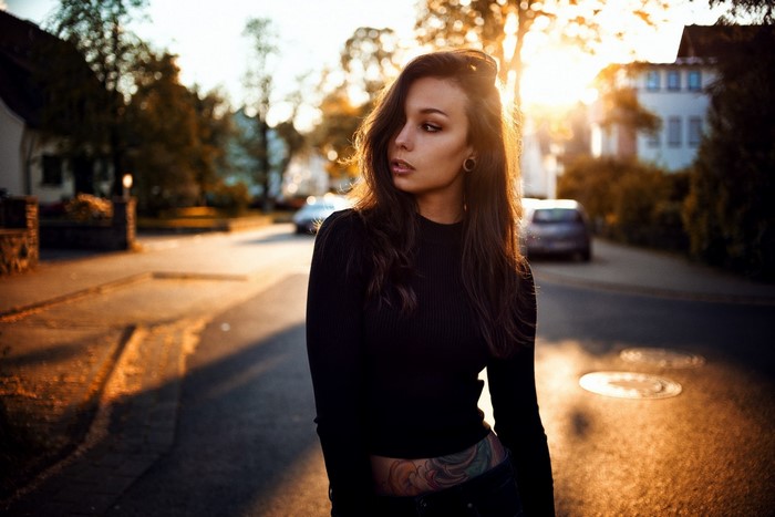 Woman with tattoo standing on a street at sunset