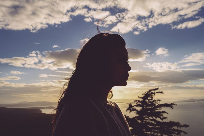 Silhouette of a woman against a cloudy sunset sky