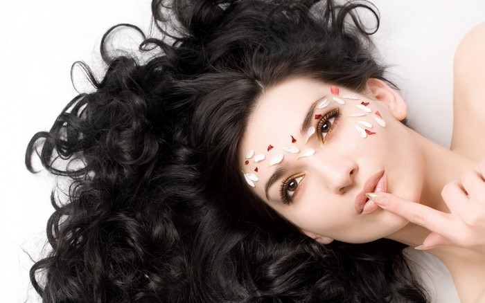 Woman with Long Curly Black Hair and Petals on Face