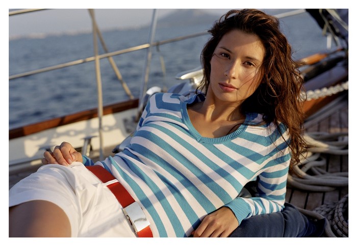 Woman in striped shirt and white shorts on a sailboat