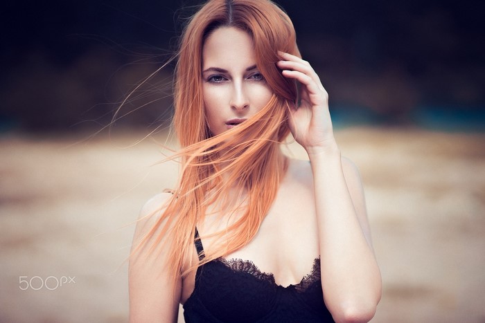 Woman with red hair in black lingerie on a beach