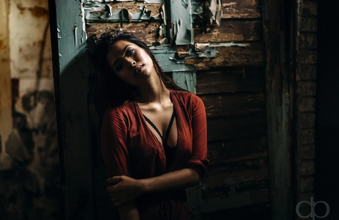 Woman in red dress leaning against a wall