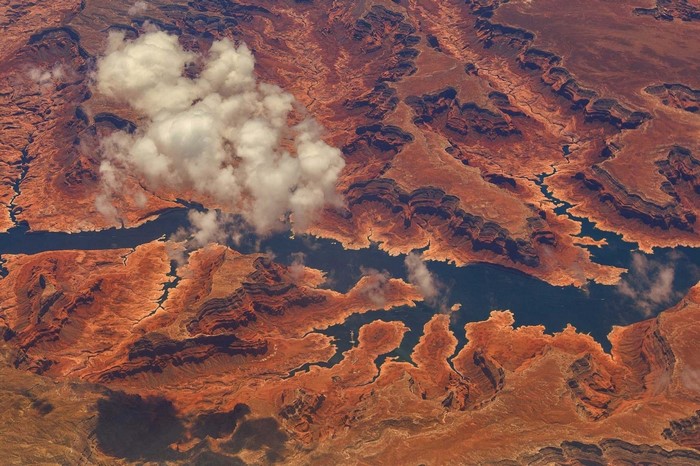 Aerial view of a desert canyon with a river and clouds