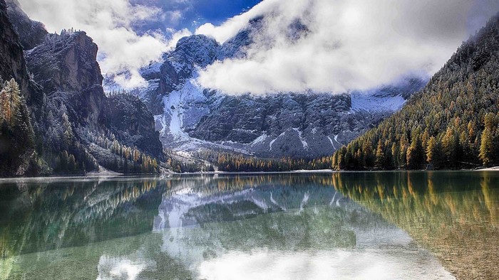 Lake with snow-capped mountains and forest in Italy