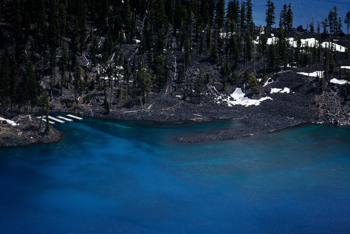 Blue lake with rocky shore and pine trees