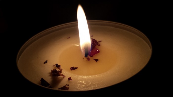 Close-up of a lit candle with flower petals