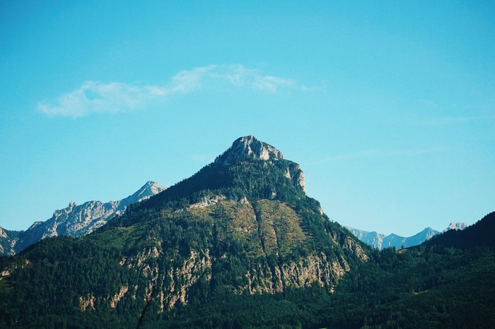 Mountain range with forested slopes and rocky summit under a blue sky