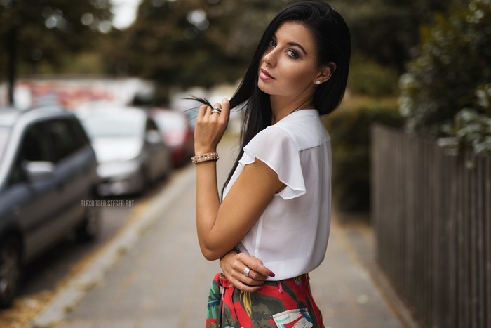 Woman with black hair wearing a white top and red floral skirt