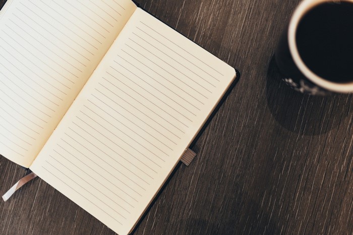 Open notebook and coffee cup on a wooden table