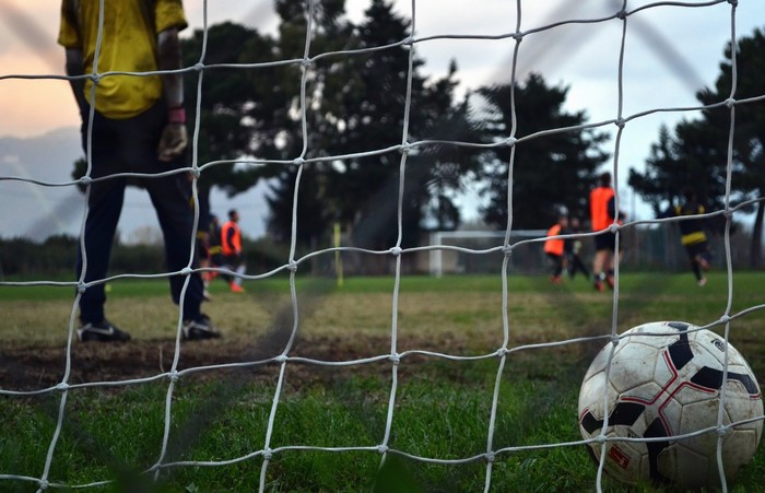 Soccer players on a field with a soccer ball in the foreground