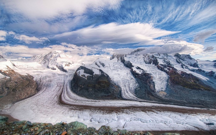 Snow-covered mountains and glaciers under a cloudy sky